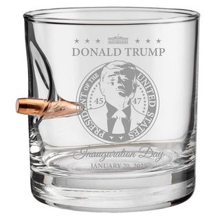 Clear whiskey glass featuring Donald Trump's inauguration design, with a bullet embedded in the side and engraved text.