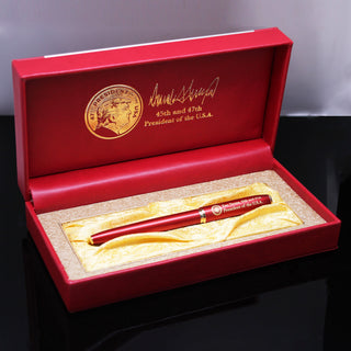 President Trump 2nd term executive order pen in a red box with gold accents and signature, displayed on a black surface.