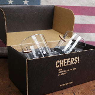 BenShot gift set featuring two clear glasses with copper accents in a black box, set against a vintage American flag backd...